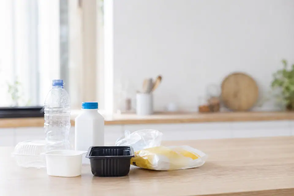 Emballages plastiques divers avec triangles de recyclage numérotés visibles, posés sur un plan de travail