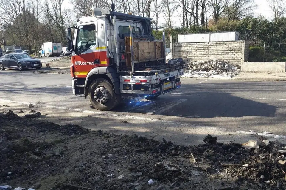 Camion benne chargé de gravats stationné devant un bâtiment en cours de réhabilitation