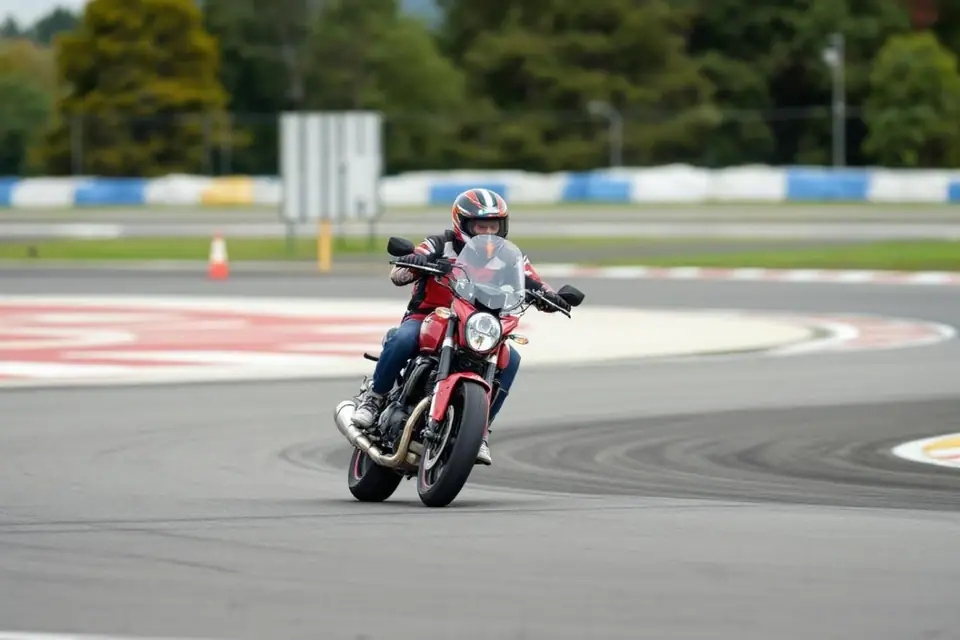 Élève motard équipé sur une moto-école, casque fermé, avant une séance pratique sur piste
