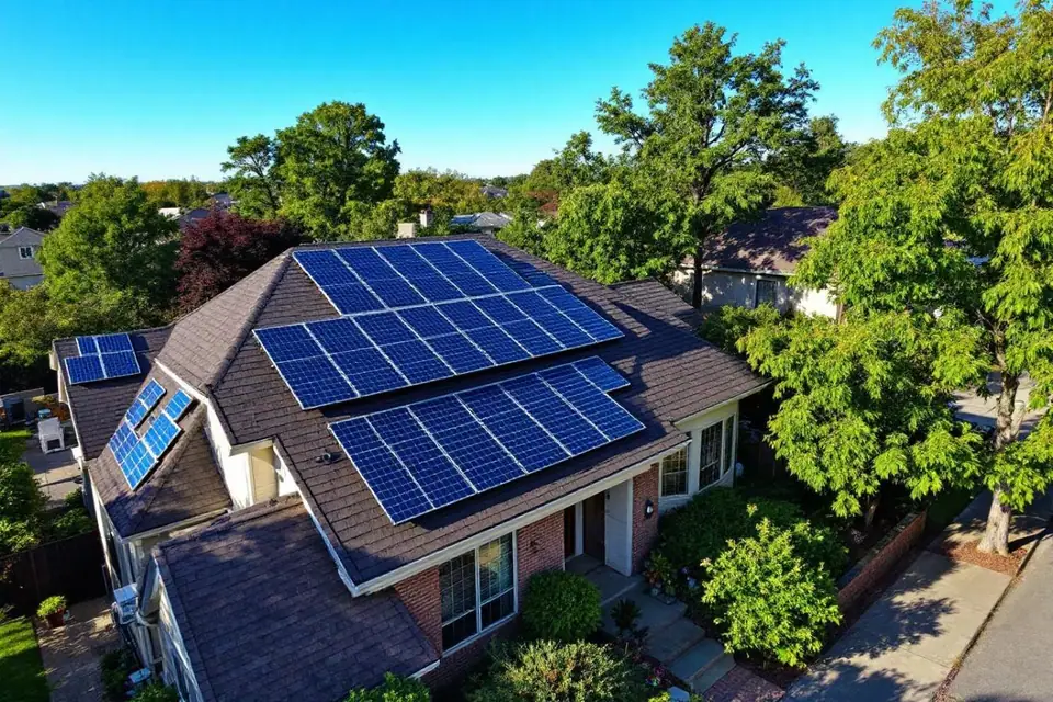 Toiture de maison équipée de panneaux photovoltaïques avec quartier résidentiel visible en arrière-plan