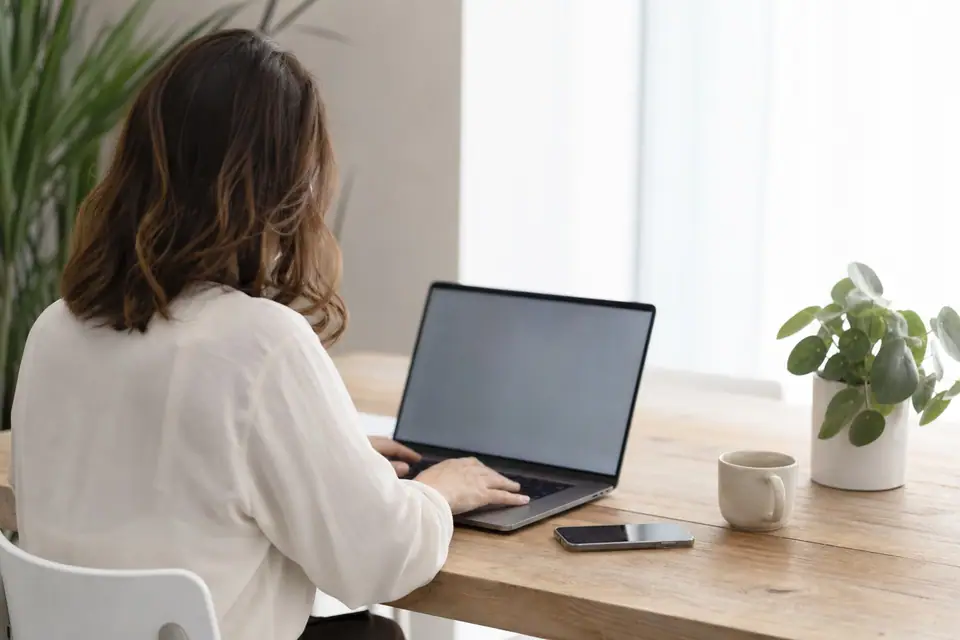 Personne consultant sa boîte email professionnelle sur un ordinateur portable, bureau lumineux