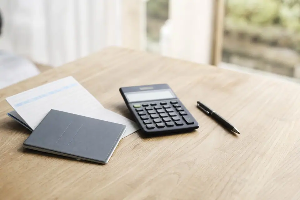Livret d’épargne et relevé bancaire posés sur une table, calculatrice à proximité