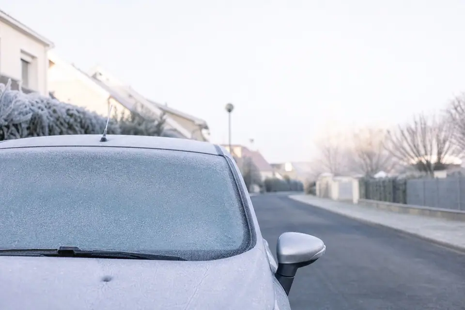 Voiture garée par temps froid, givre sur le pare-brise, capot fermé dans une rue résidentielle