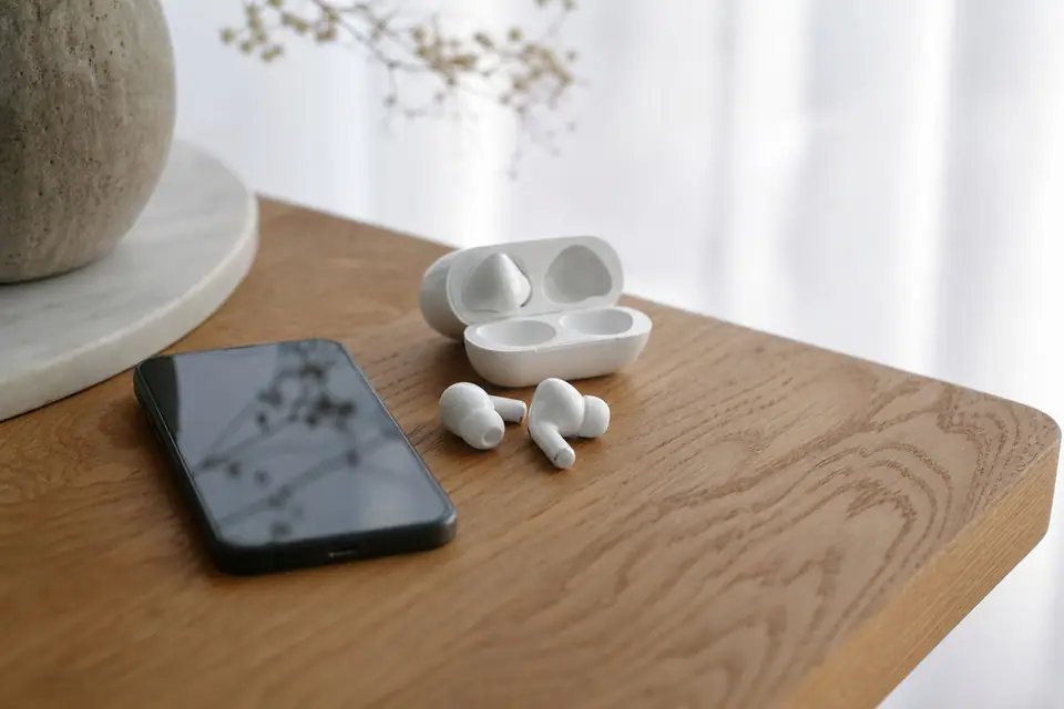 Écouteurs sans fil posés à côté d’un smartphone, boîtier de charge ouvert sur une table