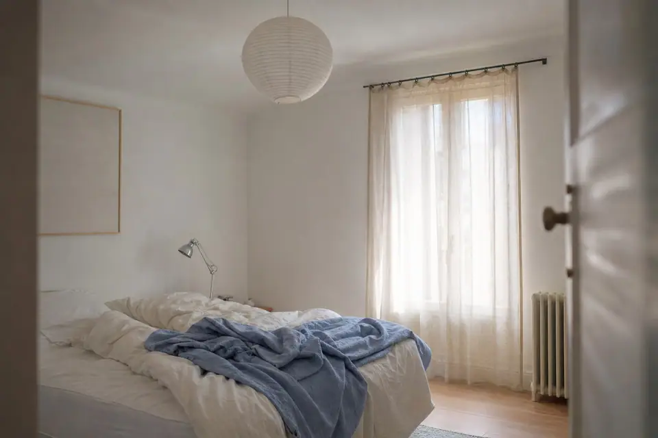 Chambre d’adolescent aux volets fermés en pleine matinée, lumière filtrant légèrement à travers les rideaux
