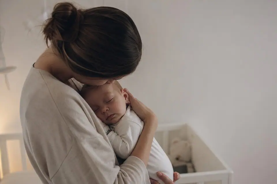 Parent tenant doucement un bébé endormi dans une chambre faiblement éclairée la nuit