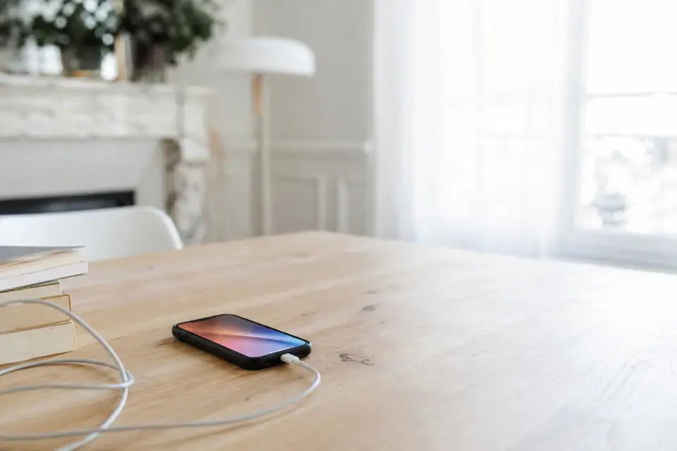 Smartphone posé sur une table en charge avec un câble branché, écran allumé
