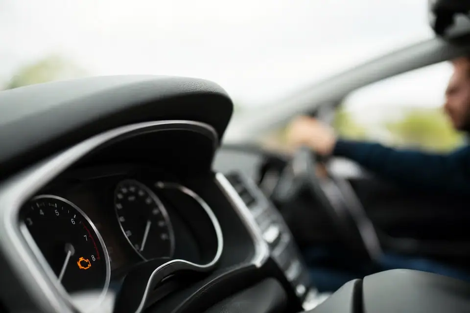 Tableau de bord de voiture avec voyant moteur allumé, gros plan sur les instruments