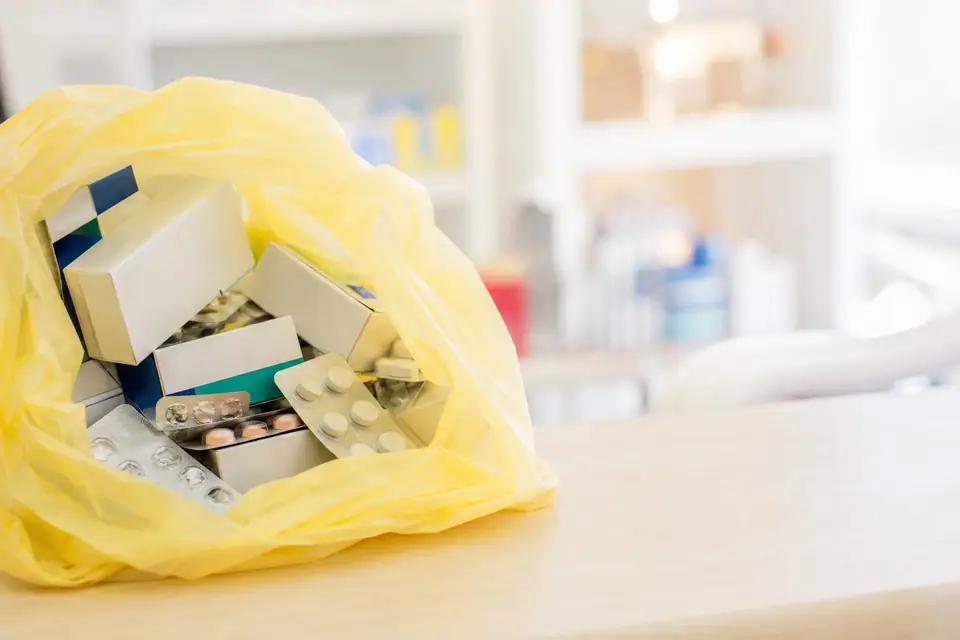 Boîtes de médicaments et plaquettes de comprimés déposées dans le sac de collecte d’une pharmacie française